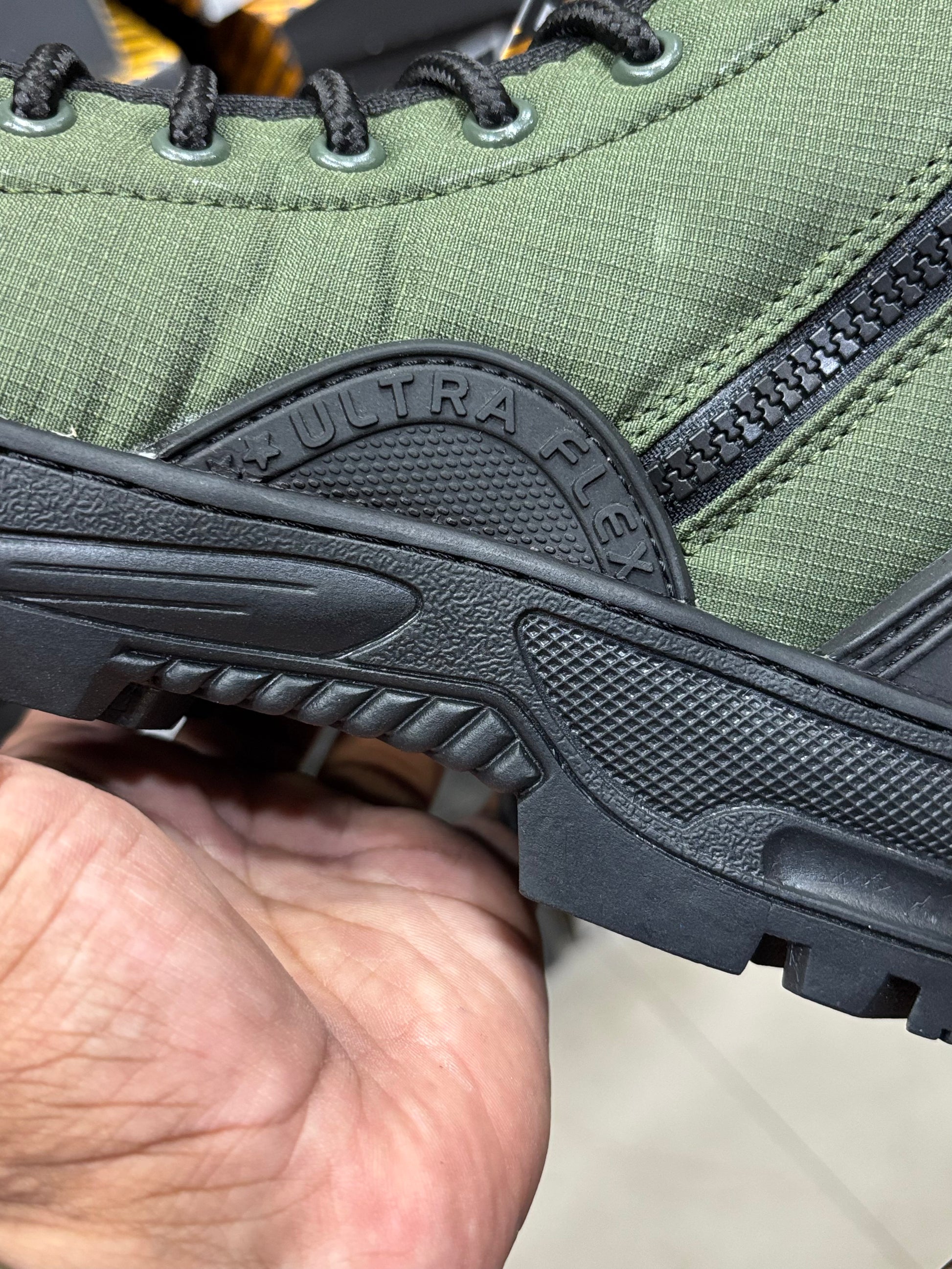 Close-up of a green hiking boot with Ultra Flex sole on a blurred background